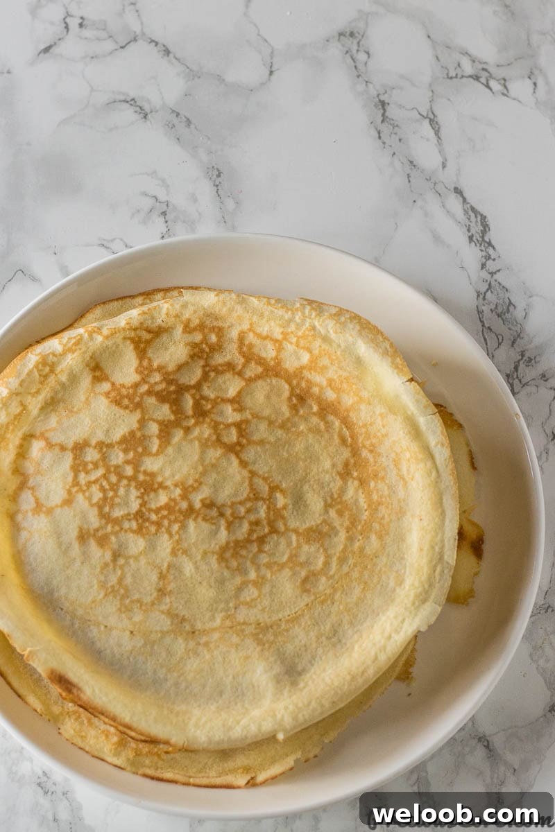 Perfect French Crepes: Thin, Tender, and Ready in Minutes 4 Thin crepes on a white plate