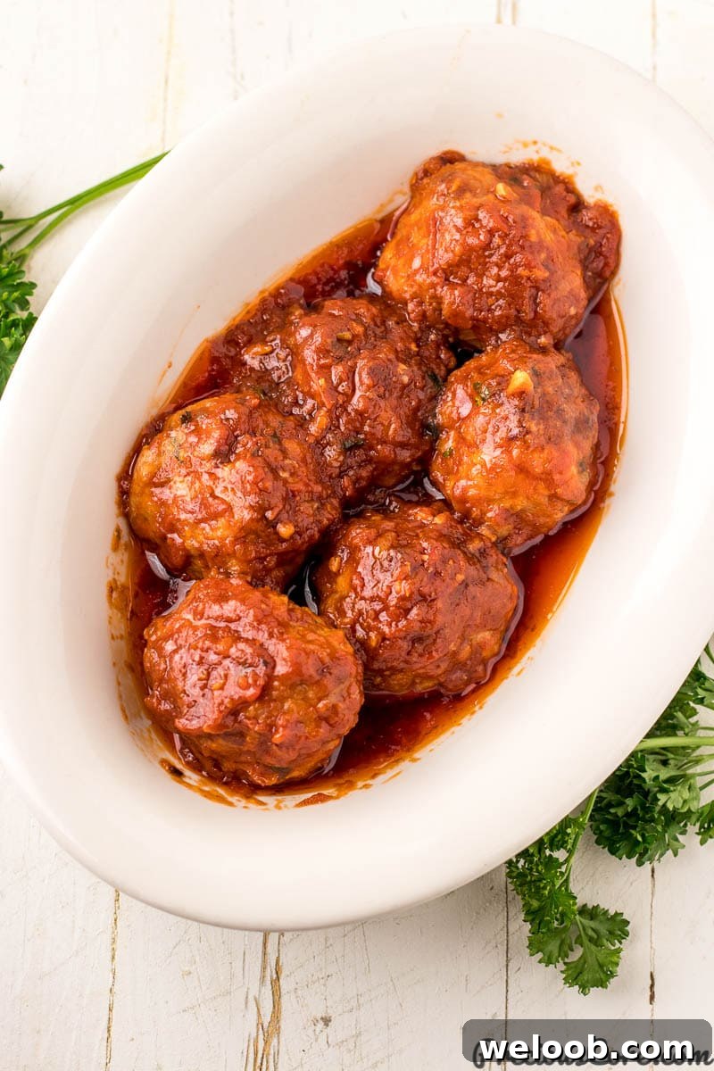 Juicy Baked Chicken Meatballs with Garlic Parmesan Sauce 4 Chicken meatballs with tomato sauce in serving bowl