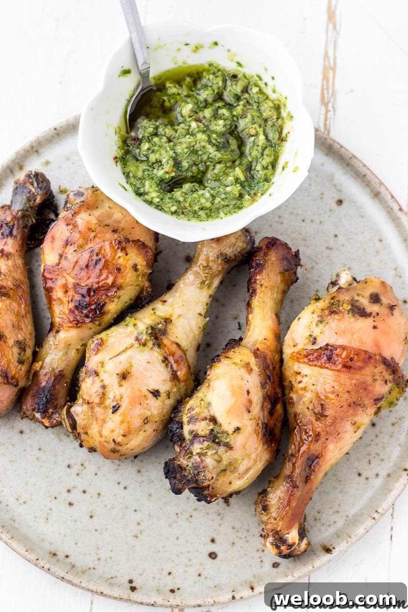 Grilled chicken on a plate with a bowl of green sauce nearby