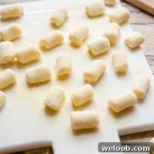A side shot of potato gnocchi on a white marble cutting board