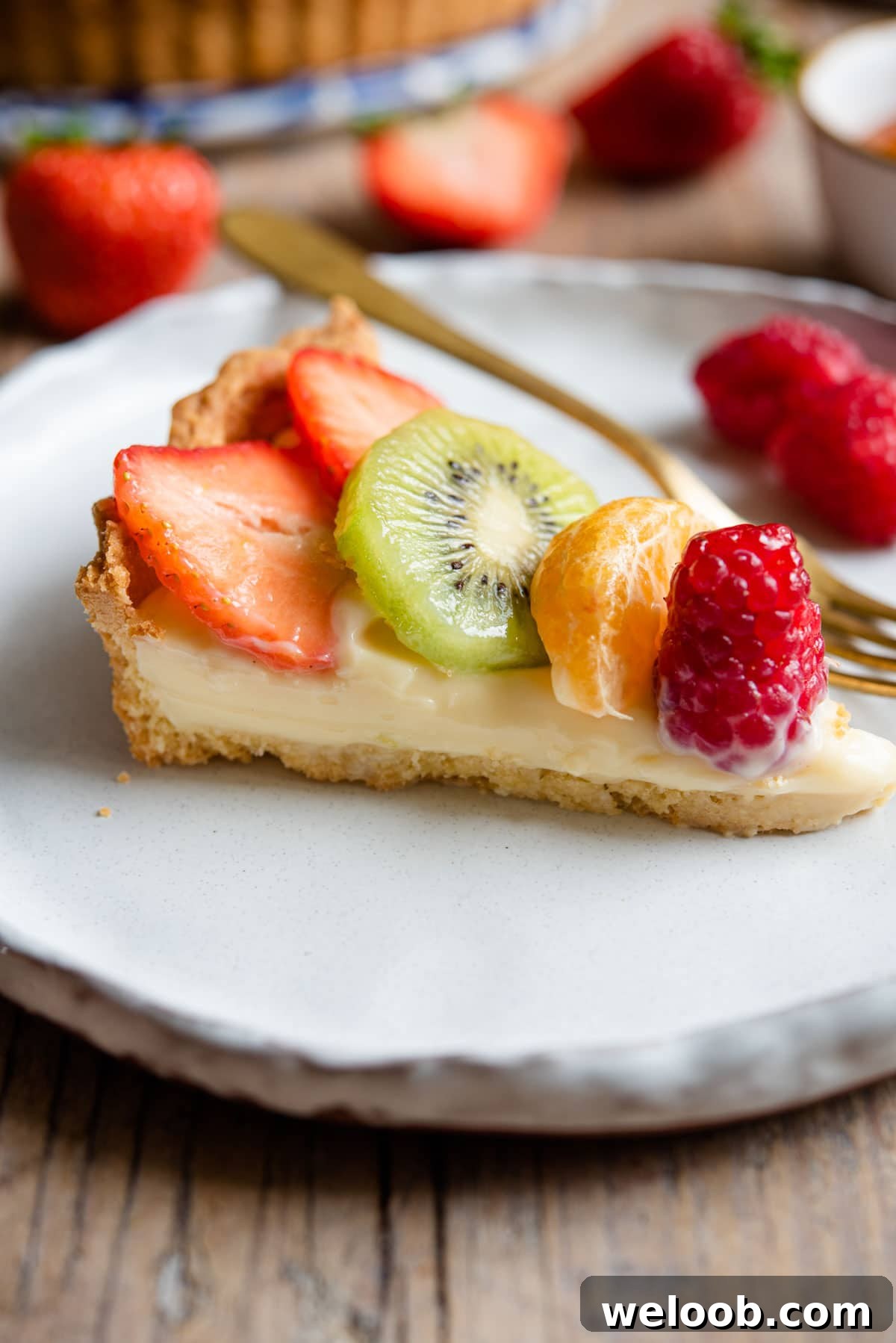 A slice of tart filled with pastry cream and fresh fruit