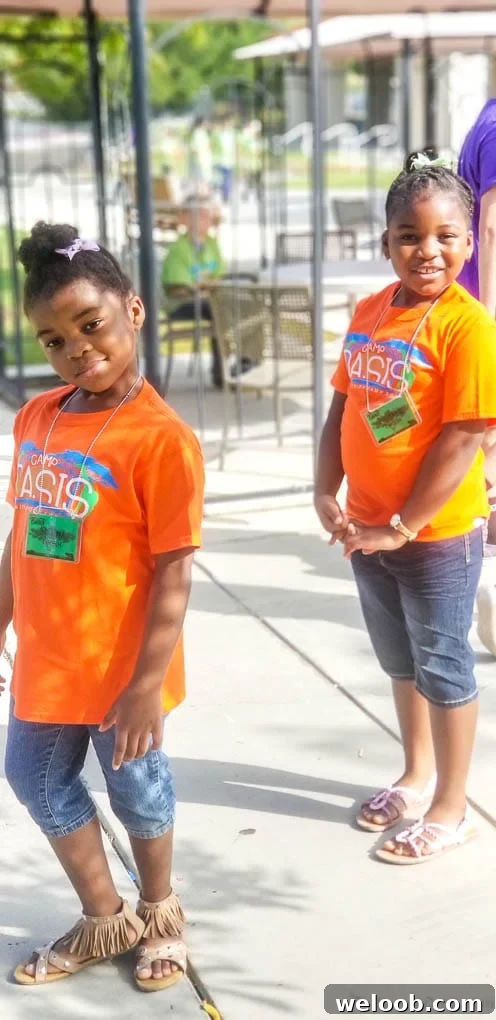 Two girls smiling in orange t-shirts.