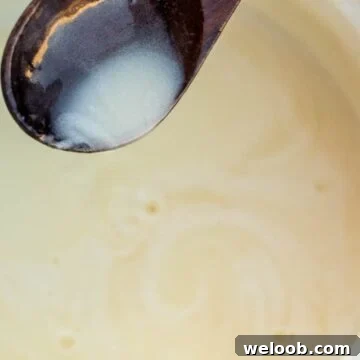 Spoon pouring bread pudding sauce