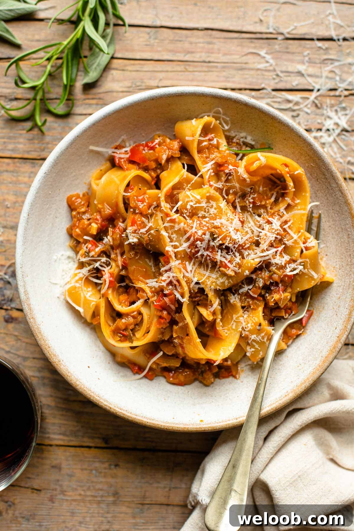 An overhead shot of a bowl of pasta with a vegetable sauce topped with parmesan cheese