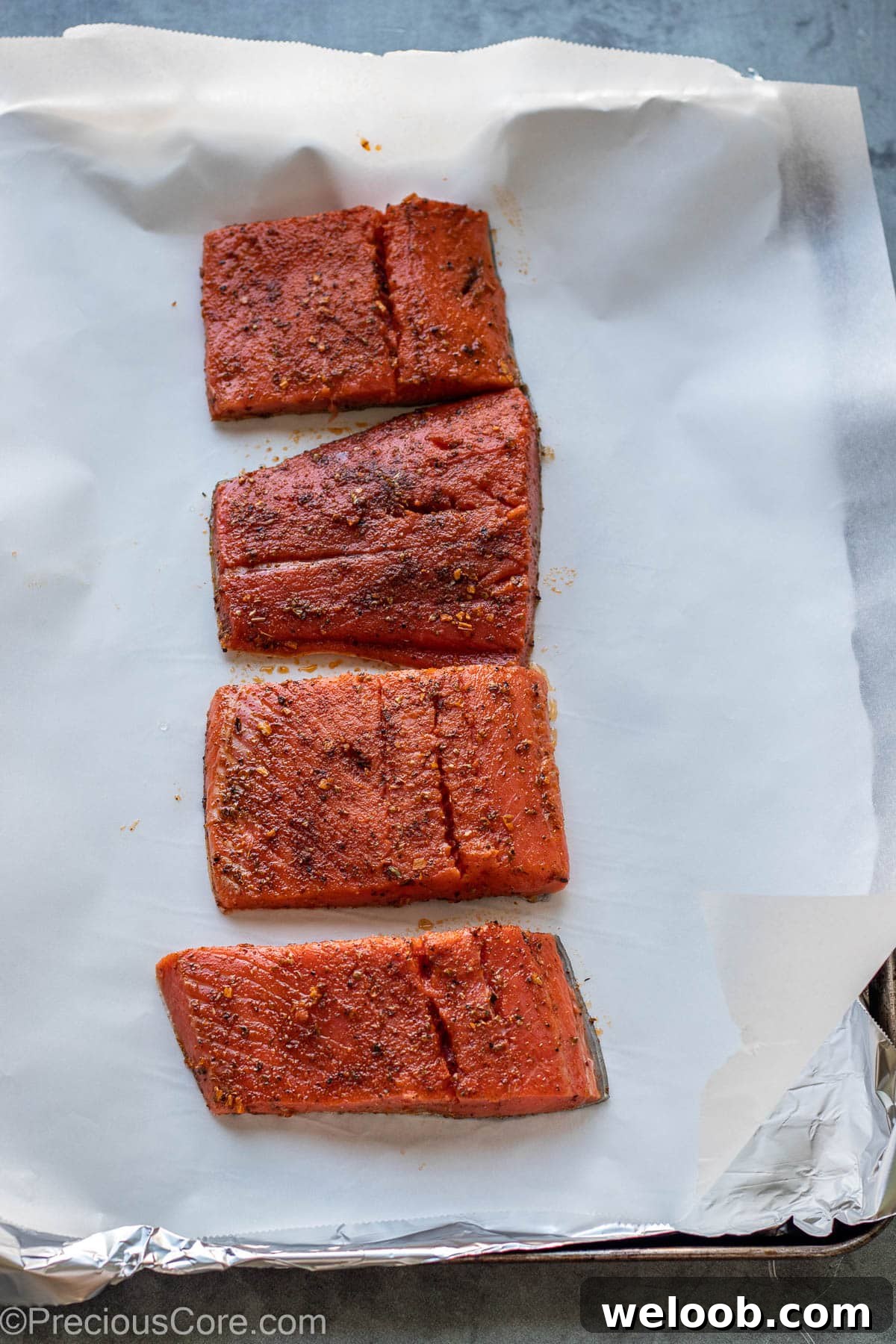 Seasoned cajun salmon placed on baking sheet for baking.