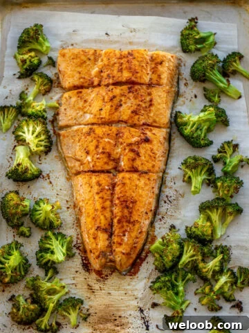 Large salmon fillet and roasted broccoli on a sheet pan