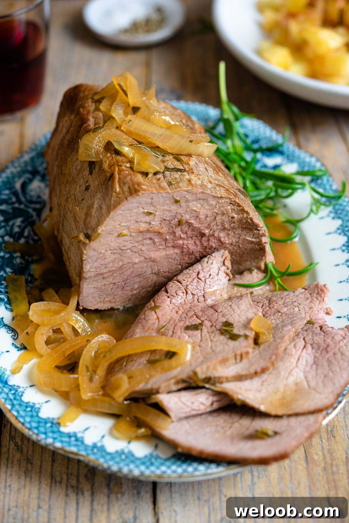 Italian roast beef on a platter with slices cut, marsala sauce and onions