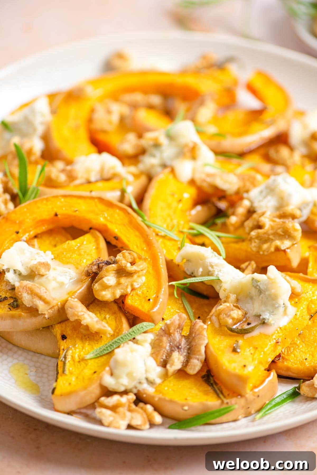 A close up of butternut squash on a serving plate with gorgonzola and walnuts
