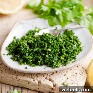Gremolata on a small plate with wedges of lemon and parsley in the background