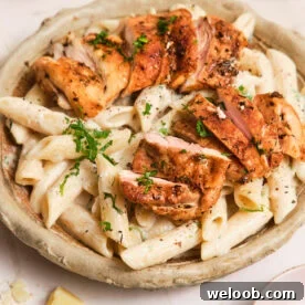 Creamy pasta in a bowl, topped with pan-seared chicken.