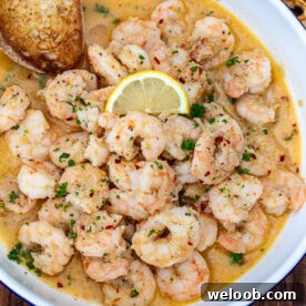 Crusty bread in a bowl of shrimp in white wine sauce.