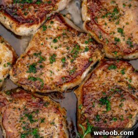 Pan seared boneless pork chops in a cast iron pan with butter underneath.