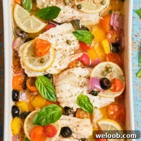 White fish fillets in a casserole dish baked with veggies.