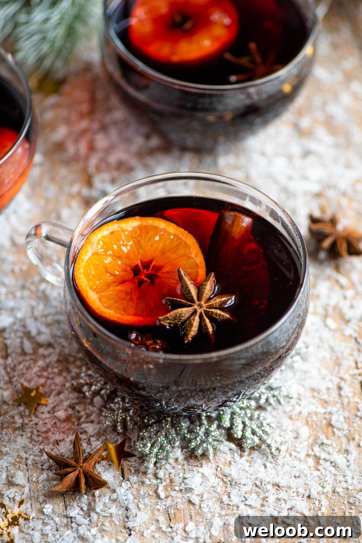 A mug of mulled wine on a snowy wooden surface