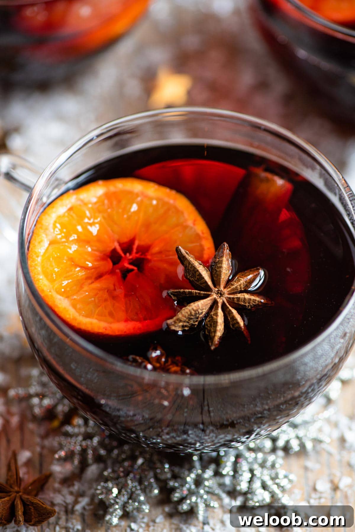 A close up of a mug of mulled wine with oranges, star anise and cinnamon