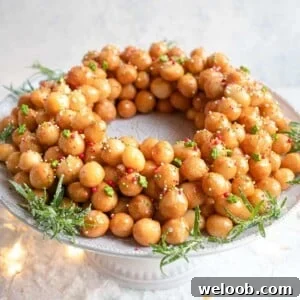 Struffoli honey balls in a ring shape on a cake stand covered in sprinkles