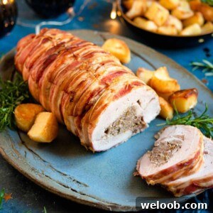 A close up of a stuffed turkey breast on a platter with roast potatoes