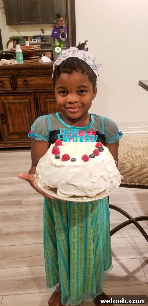 Girl wearing an Anna dress holding a cake that says "Happy Birthday."
