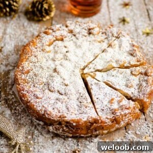 A close up of panforte on a wooden board dusted with powdered sugar