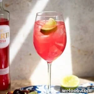 A close up cropped image of a sarti spritz garnished with lime.