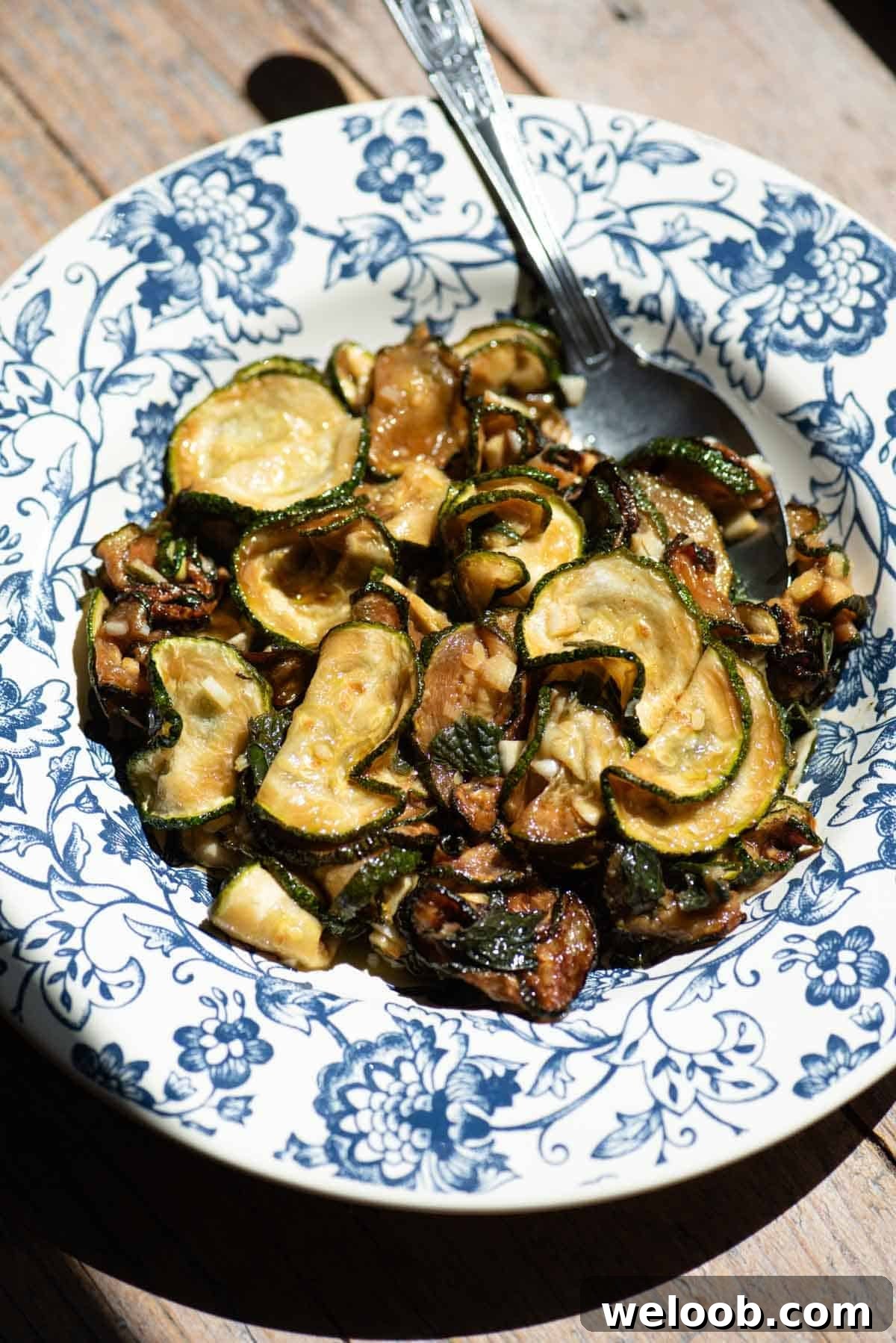 Zucchine alla Scapece: Neapolitan Marinated Zucchini 2 A blue and white floral bowl filled with fried marinated zucchini and a spoon.