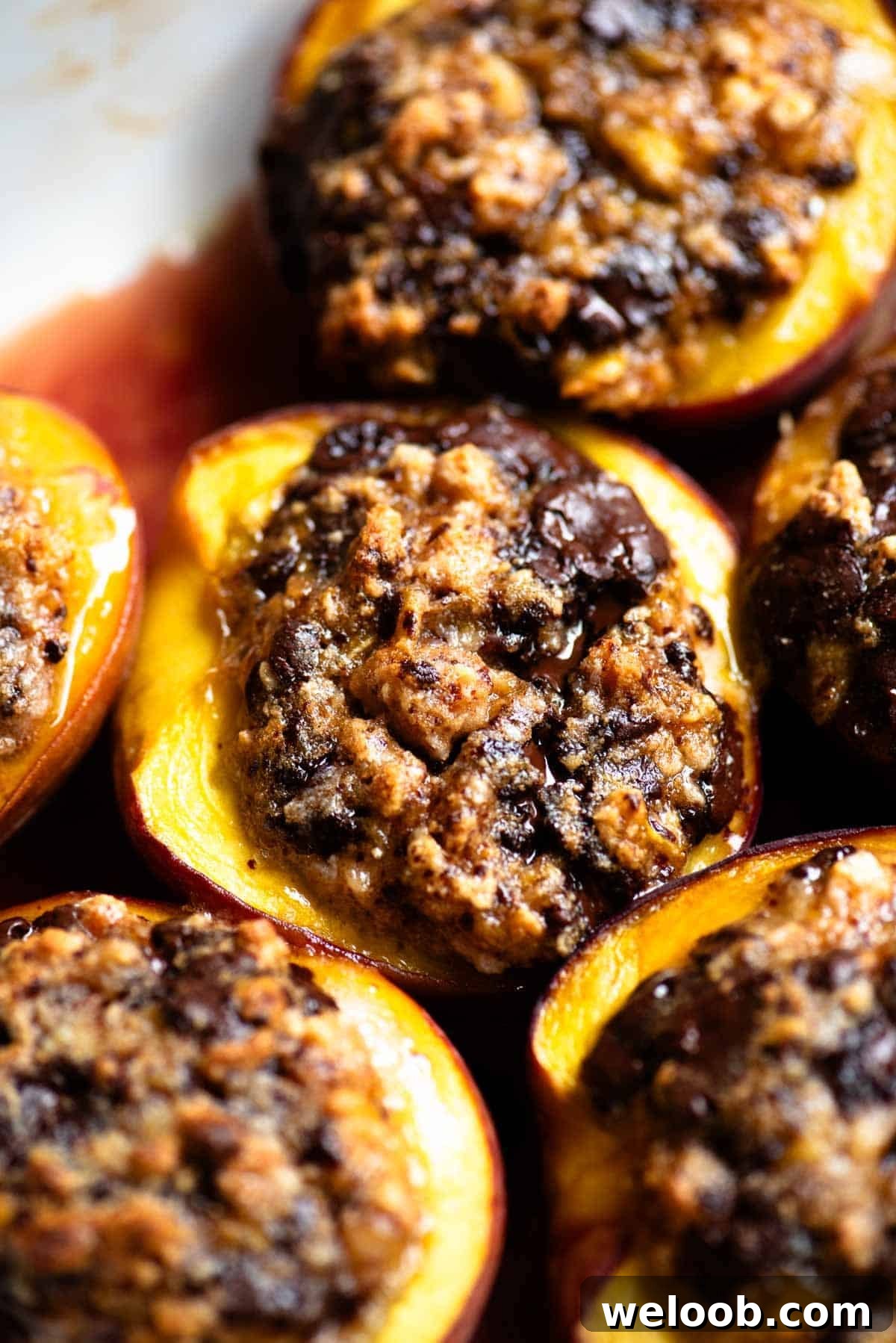 A close up of a baked peach stuffed with amaretti cookies and chocolate in a baking dish.