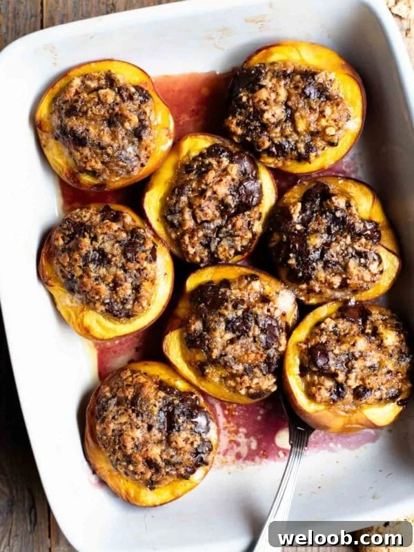 Torta Nua: Rustic Italian Cake Filled with Pastry Cream 5 An overhead shot of baked peaches stuffed with amaretti cookies and chocolate in a white baking dish on a rustic wooden background.