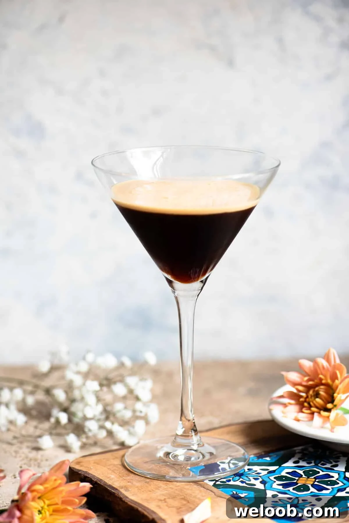 Caffè Shakerato: Classic Italian Iced Coffee Recipe 15 A martini glass filled with an Italian iced coffee sitting on a wooden table with flowers around.