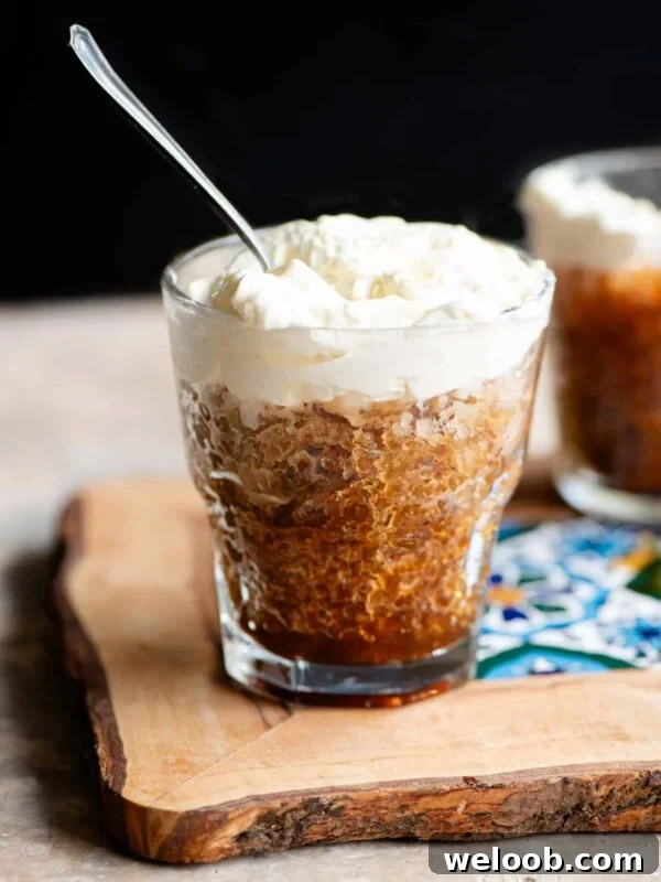 A small glass of coffee granita topped with whipped cream and a spoon in it.