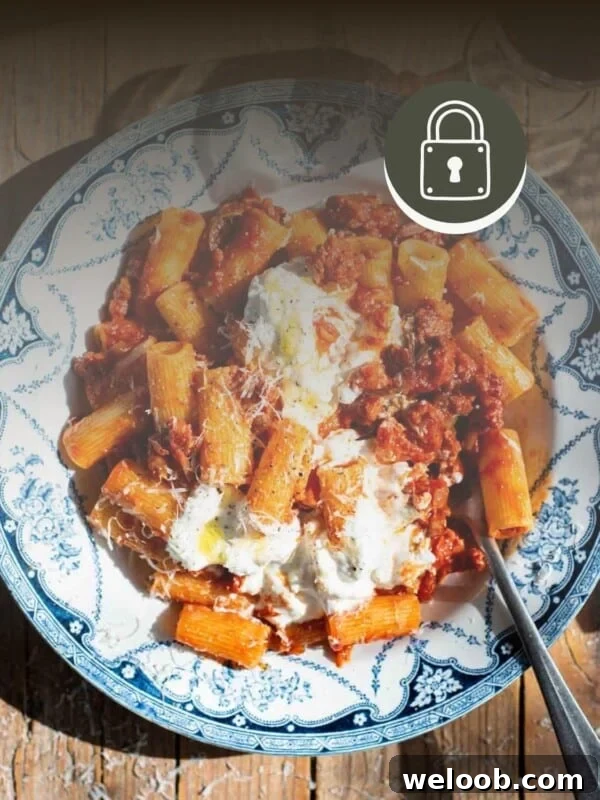 Spicy Calabrian sausage ragu in a blue and white bowl with stracciatella on top.