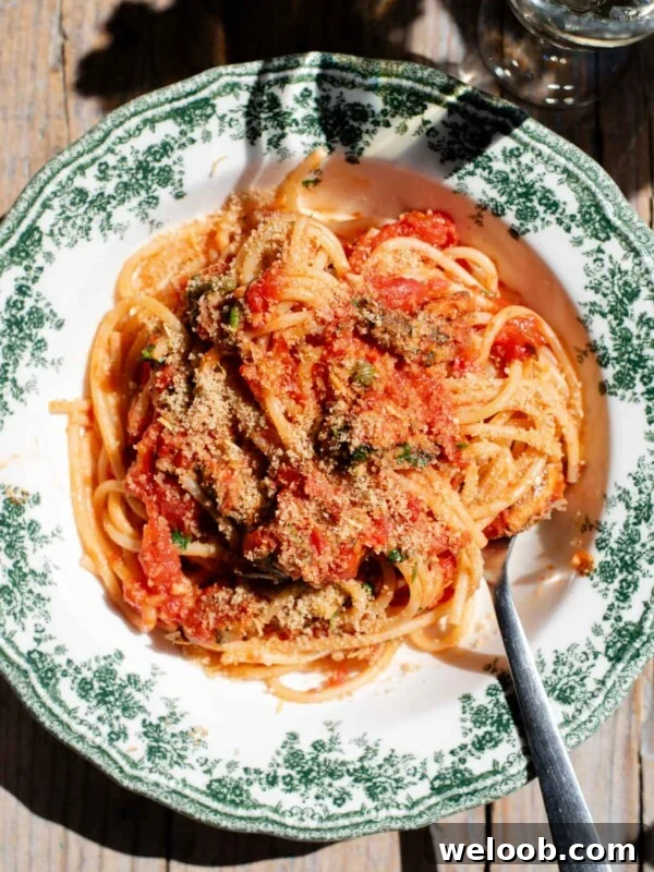 An overhead shot of spaghetti in a tomato sauce with sardines and breadcrumbs on top.