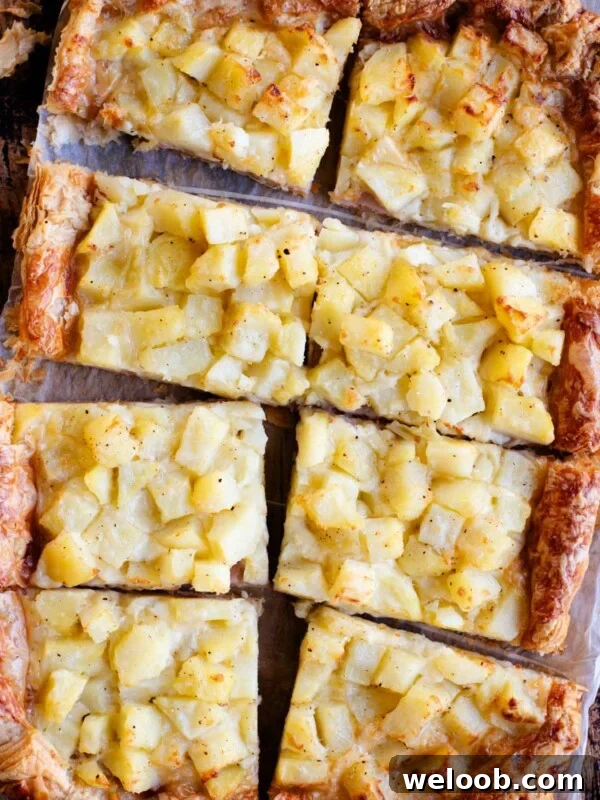 An overhead shot of a puff pastry tart topped with potatoes, ham and cheese and cut into 8 slices.