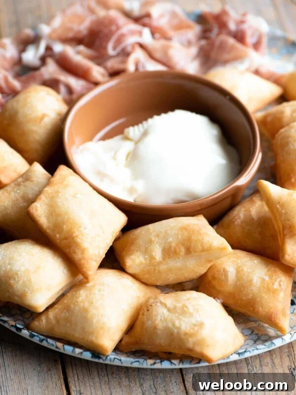 Gnocco Fritto (Italian fried dough) on a plate with cheese and prosciutto.